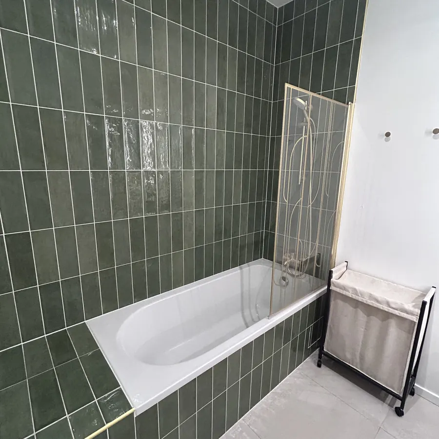 Baignoire avec paroi de douche vitrée et faïence verte zellige
