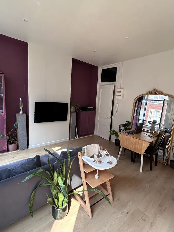 Coin repas du séjour avec table, miroir doré et téléviseur